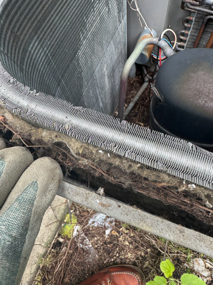HVAC technician cleaning a dirty outdoor heat pump condenser coil in Beacon, NY for routine maintenance and improved energy efficiency.