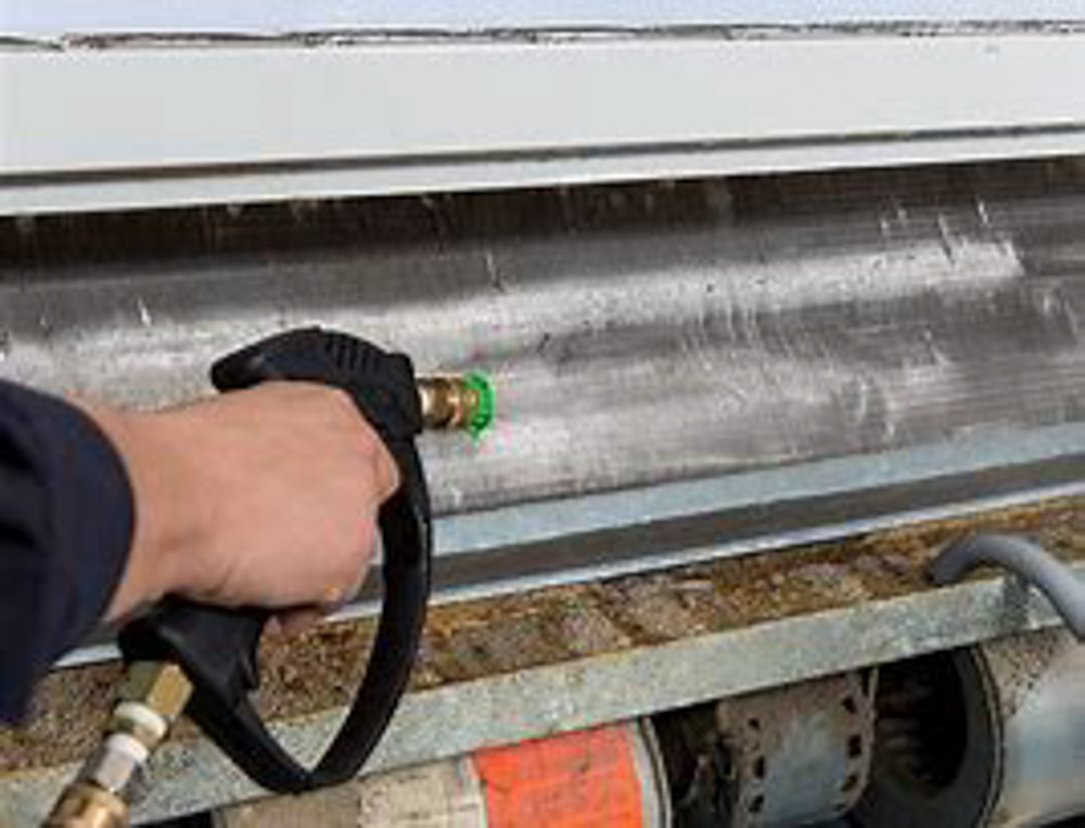 Technician spraying water to clean dirty mini split coil during HVAC deep cleaning.