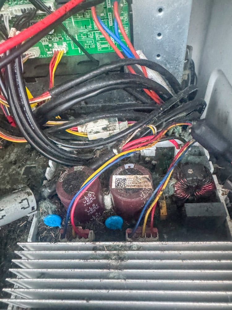 Close-up image of rodent nesting debris and contamination inside an HVAC condenser, with chewed wires and dirt covering the interior, showing serious indoor air quality and equipment reliability hazards.
