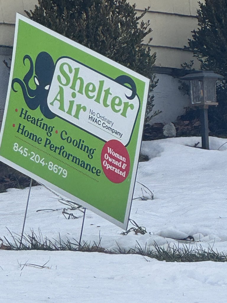Shelter Air yard sign in snow outside a home, advertising heating, cooling, and home performance services by a woman-owned HVAC company in the Hudson Valley.